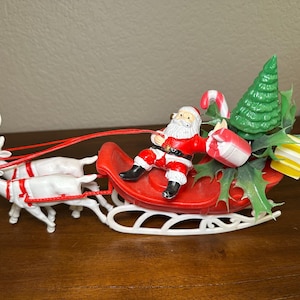 Vintage plastic kerstman in slee met twee rendieren, ingepakte pakjes, zuurstokken en kerstboom