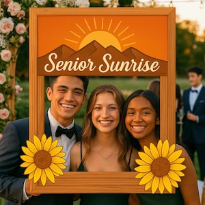 May include: A wooden frame with the text "Senior Sunrise" and a sunset design, held by three smiling people. The frame has two yellow sunflower cutouts. The people are dressed in formal attire.