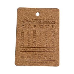 Puede incluir: Un posavasos de corcho marrón con una tabla de conversión de cocina impresa en él. La tabla incluye medidas para tazas, onzas, gramos, cucharadas, cucharaditas y mililitros. También incluye una tabla de conversión de temperatura.