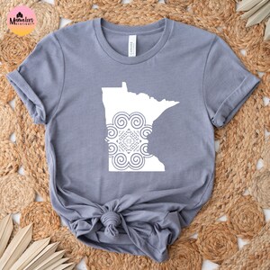 May include: A gray t-shirt with a white outline of the state of Minnesota with a stylized geometric design inside.