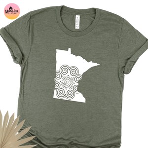 May include: A green t-shirt with a white outline of the state of Minnesota with a mandala design inside.