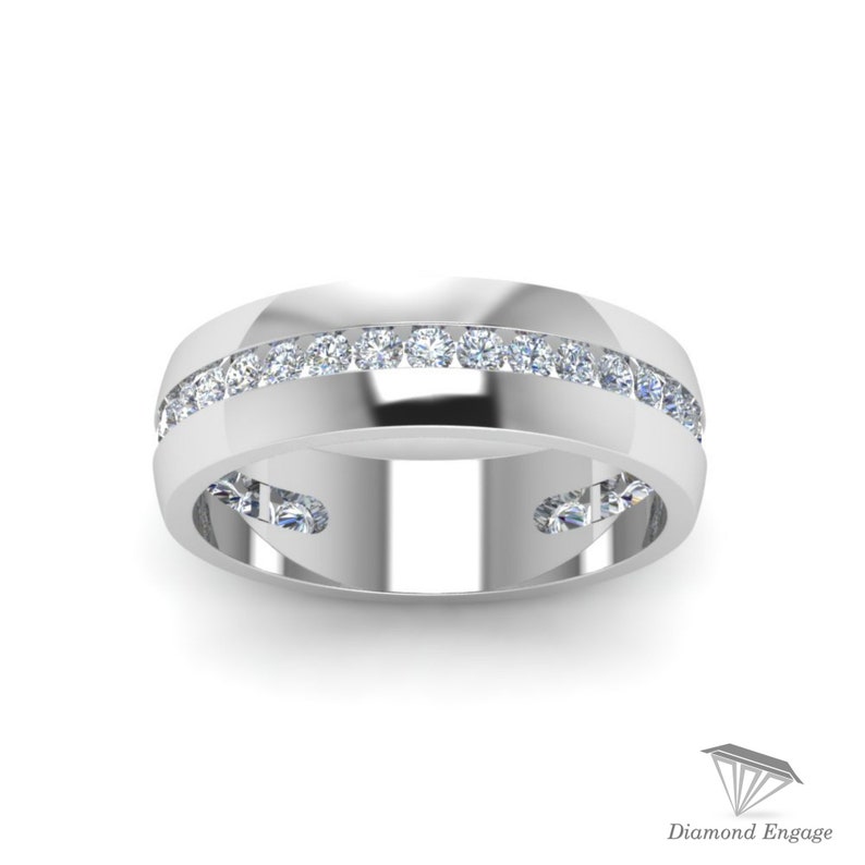 May include: A white gold ring with a row of small, clear gemstones set into the band. The ring has a polished finish and a modern design, suitable for a wedding or engagement. The ring is displayed on a white background.