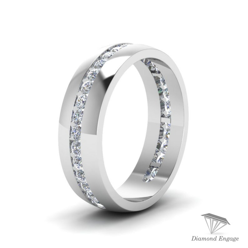 May include: A polished, silver-toned ring with a channel setting. The ring features two parallel rows of small, clear gemstones. The design is simple and elegant, with a high-shine finish. The ring is set against a white background.