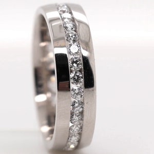 May include: A close-up of a silver ring with a channel of small, round diamonds. The ring is set against a white background, with the brand name "Diamond Engage" visible in the lower right corner.