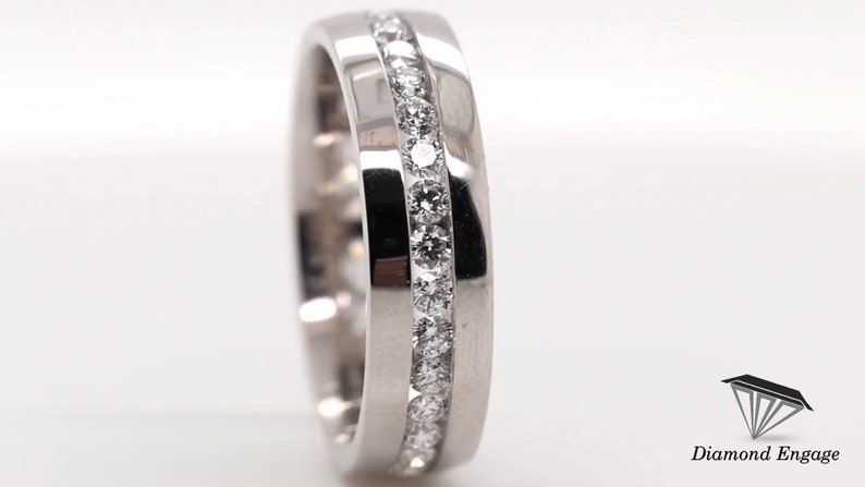 May include: A close-up of a silver ring with a channel of small, round diamonds. The ring is set against a white background, with the brand name "Diamond Engage" visible in the lower right corner.