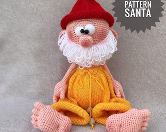 Pode incluir: Padrão de crochê para um gnomo Papai Noel. O gnomo está sentado com um chapéu vermelho, barba branca, calças amarelas e pés cor-de-rosa. O padrão é chamado "Crochet Pattern Santa".