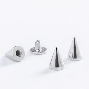 Può includere: Una collezione di borchie a cono in metallo color argento e un perno a vite, ideali per aggiungere un elemento decorativo a vestiti o accessori. Le borchie hanno un design a punta e il perno a vite è progettato per fissare le borchie.