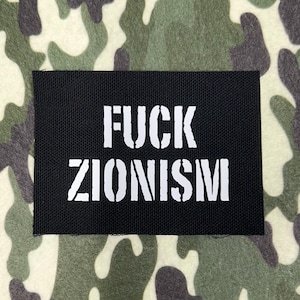 May include: A black rectangular patch with the words "FUCK ZIONISM" in bold white stencil font. The patch is set against a camouflage pattern background in shades of green, brown, and beige.