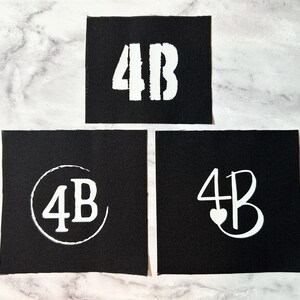May include: Three black fabric patches with white lettering. The first patch says "4B" in a bold, blocky font. The second patch says "4B" in a circle. The third patch says "4B" with a heart in the middle of the "4".