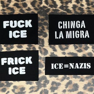 May include: Four black rectangular patches with white text. The patches read "FUCK ICE", "CHINGA LA MIGRA", "FRICK ICE", and "ICE=NAZIS". The background is a leopard print pattern.