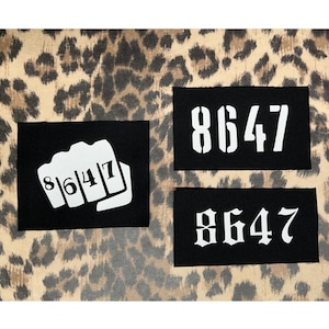 May include: Three black rectangular patches with the number "8647" in white. One patch features the number within a fist graphic. The background is a tan and brown leopard print pattern.
