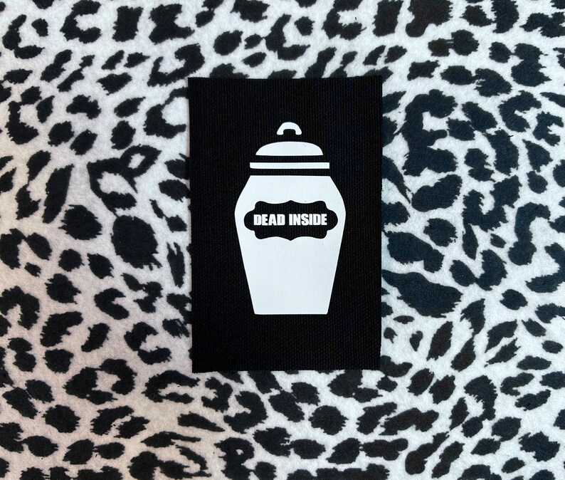 May include: Black patch with a white silhouette of a jar with the text "DEAD INSIDE" on a label.