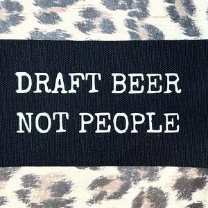 Könnte beinhalten: Schwarzer Stoff-Patch mit weißem Text, der "DRAFT BEER NOT PEOPLE" lautet.