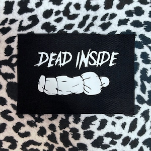 May include: Black fabric patch with white text that reads "DEAD INSIDE" and a white cartoon image of a hand.