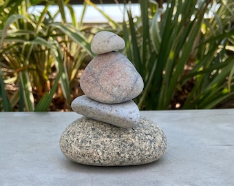May include: A stack of four gray and white stones, balanced on top of each other, creating a small rock cairn.