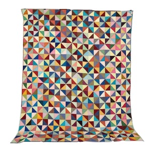 Könnte beinhalten: Eine große, farbenfrohe Steppdecke mit einem geometrischen Muster aus Dreiecken in verschiedenen Farben, darunter Blau, Rot, Gelb und Grün. Die Steppdecke ist aus Stoff und wird vor einem weißen Hintergrund präsentiert.