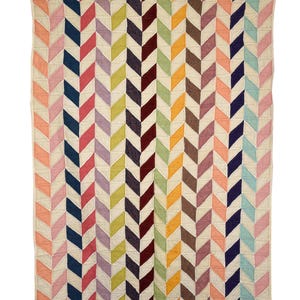 May include: A colorful quilt with a repeating chevron pattern. The design features rows of multi-colored chevrons in shades of pink, blue, purple, green, orange, and brown, set against a cream-colored background. The quilt is made of a soft, textured fabric.