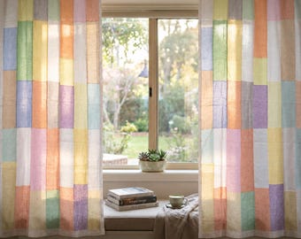May include: A pair of tab-top curtains featuring a patchwork design of vertical rectangular panels in soft pastel shades of yellow, orange, pink, purple, blue, and green. The curtains are hung on a metal rod, displaying a semi-sheer fabric texture.