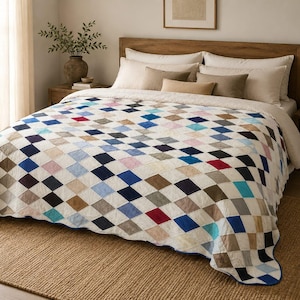 Könnte beinhalten: Eine Tagesdecke mit einem sich wiederholenden Rautenmuster in Blau-, Rot-, Braun-, Schwarz- und Cremetönen. Die Steppdecke liegt auf einem Bett mit mehreren Kissen, darunter cremefarbene, beige und braune rechteckige Kissen.