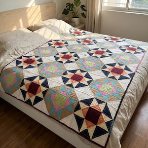 Puede incluir: Un edredón colorido con un patrón de estrellas geométricas, exhibido en una cama. El edredón presenta un diseño de patchwork con varios colores, incluyendo azul marino, beige, burdeos, rosa y verde. El edredón está bordeado con un ribete rojo oscuro.