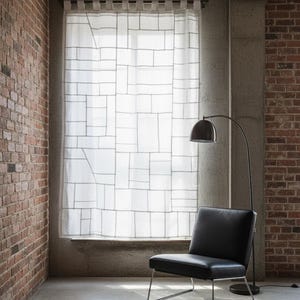 Może przedstawiać: Nowoczesne wnętrze z czarnym skórzanym krzesłem z chromowaną ramą, lampą podłogową i oknem z geometrycznym wzorem zasłony. Pokój ma odsłonięte ściany z cegły i betonu oraz polerowaną betonową podłogę.