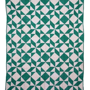 Op de afbeelding: Een handgemaakte quilt met een geometrisch sterrenpatroon in wit en smaragdgroen. De quilt wordt hangend getoond, waarbij de ingewikkelde stiksels en het ontwerp worden getoond. De afmetingen van de quilt zijn niet zichtbaar.