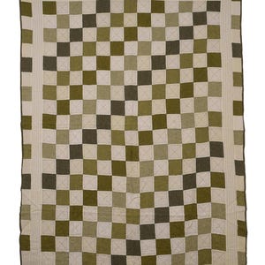 Könnte beinhalten: Ein rechteckiger Quilt mit einem Schachbrettmuster aus abwechselnden olivgrünen, dunkelwaldgrünen und cremefarbenen Stoffquadraten. Der Quilt ist mit einem breiten cremefarbenen Rand versehen und mit sichtbaren weißen Steppstichen verziert.