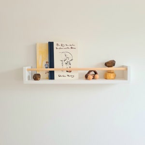 Scandi nursery wall shelf in white wood with oak rail, perfect for displaying baby shower gifts and décor