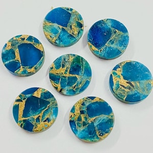 May include: Seven circular gemstones with a polished finish. The stones display a mosaic pattern of deep blue, teal, and gold. They are arranged on a white surface, highlighting their unique textures. Suitable for jewellery making or crafts.