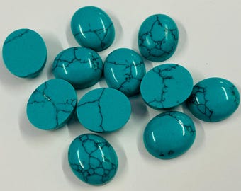 May include: A selection of turquoise cabochons with dark veining. The gemstones are oval and round, with a polished, glossy finish. The cabochons are arranged on a white surface.