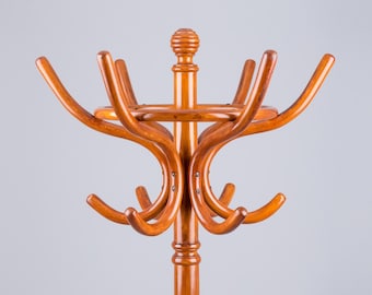 Può includere: Un appendiabiti in legno con una base rotonda e più ganci curvi. L'appendiabiti è in legno marrone chiaro e ha un design semplice e classico.