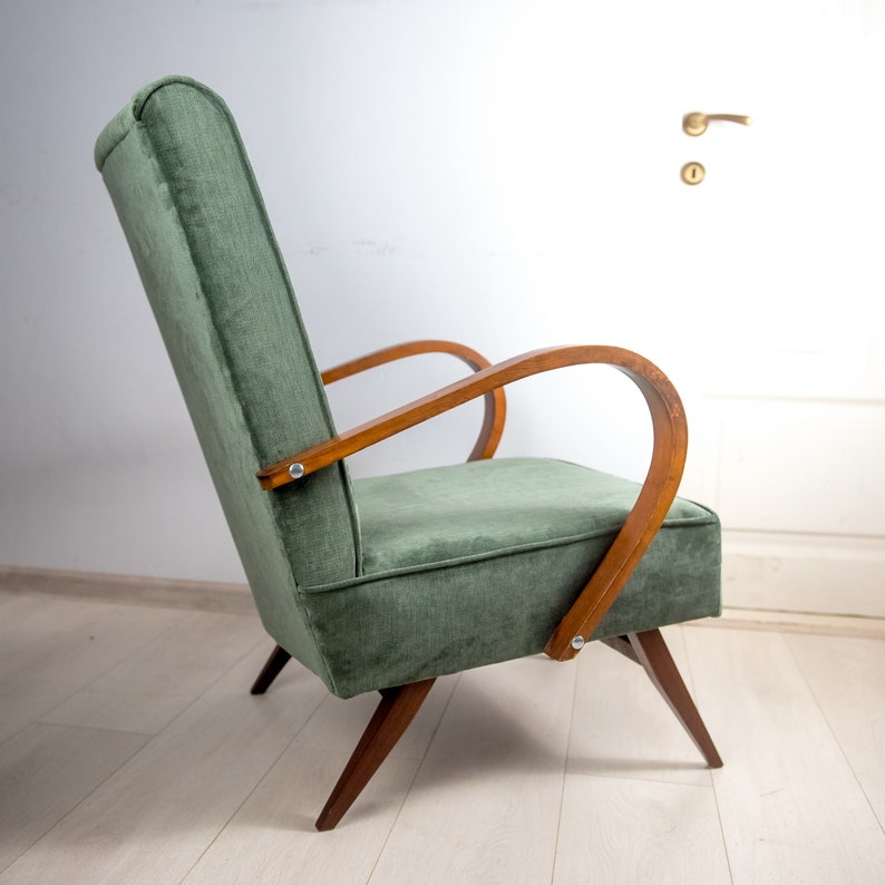 May include: A green upholstered armchair with wooden arms and legs. The chair has a high back and a curved shape.