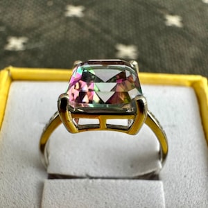 May include: A silver ring with a large, square-shaped, iridescent gemstone set in a gold setting.