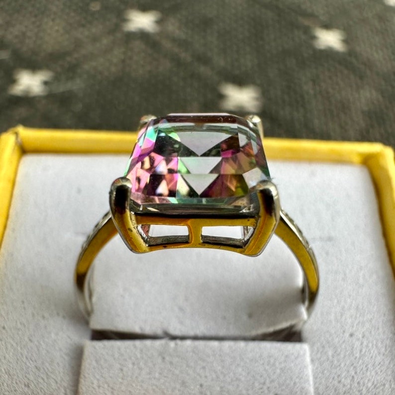 May include: A silver ring with a large, square-shaped, iridescent gemstone set in a gold setting.