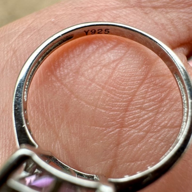 May include: Close-up of the inside of a silver ring with the inscription "Y925" on the band.