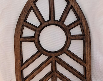 May include: A dark brown wooden wall decor piece shaped like an arched window with a geometric design. The design features a circle in the center surrounded by triangles and a chevron pattern at the bottom.