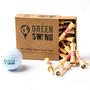 Peut inclure: Une boîte de 20 tees de golf en bambou avec des rayures roses. La boîte est ouverte et les tees se répandent. La boîte est étiquetée "GREEN SWING 20 x 60 mm Tees de golf en bambou Solides, durables et biodégradables". Une balle de golf blanche avec le logo GREEN SWING est au premier plan.