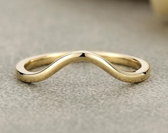May include: A polished yellow gold ring featuring a smooth, curved wave-like band. The metal has a reflective, high-shine finish with a continuous, solid construction that forms a gentle arch shape, showcasing a clean and simple design aesthetic.