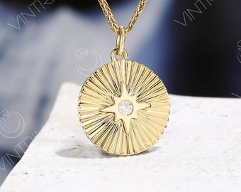 May include: A gold necklace with a round pendant featuring a starburst design with a small clear stone in the center.