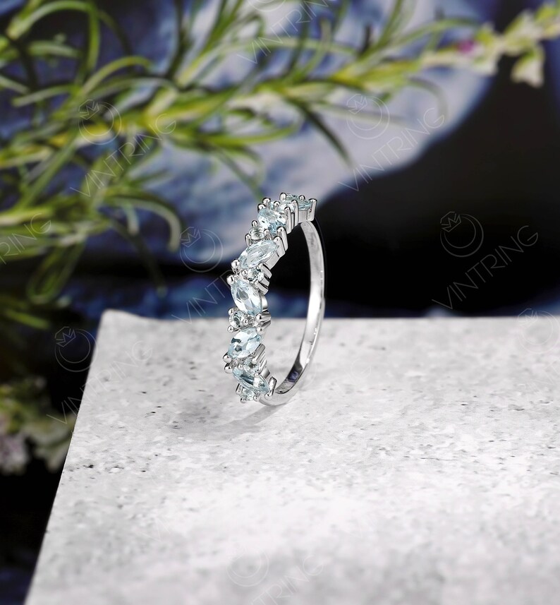 May include: A silver ring with a row of light blue marquise-shaped gemstones set in a delicate band.