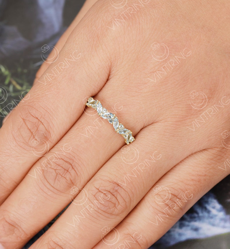 May include: A gold band ring with a row of marquise-shaped clear stones set in a pave setting.