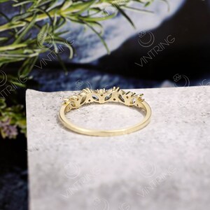 May include: A gold band ring with a row of small, clear, marquise-shaped stones set in the band.