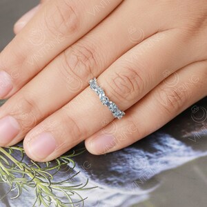 May include: A silver band ring with a row of pear-shaped clear stones set in a curved design.