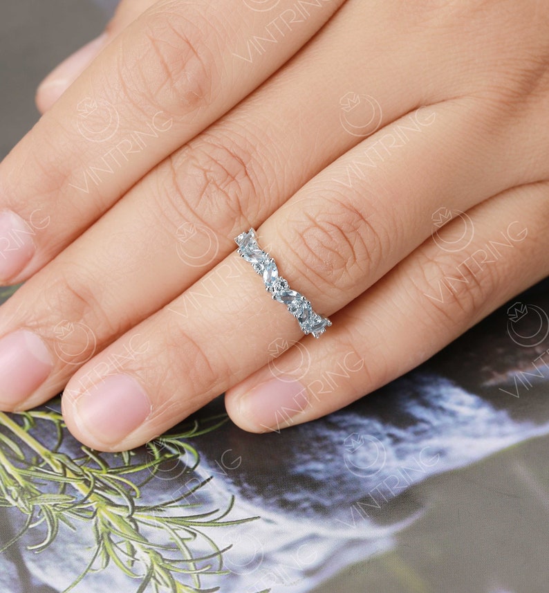 May include: A silver band ring with a row of pear-shaped clear stones set in a curved design.