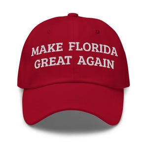 May include: Red baseball cap with white embroidered text that reads "Make Florida Great Again".