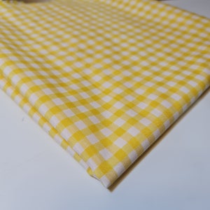 May include: Yellow and white gingham fabric with a checkered pattern.