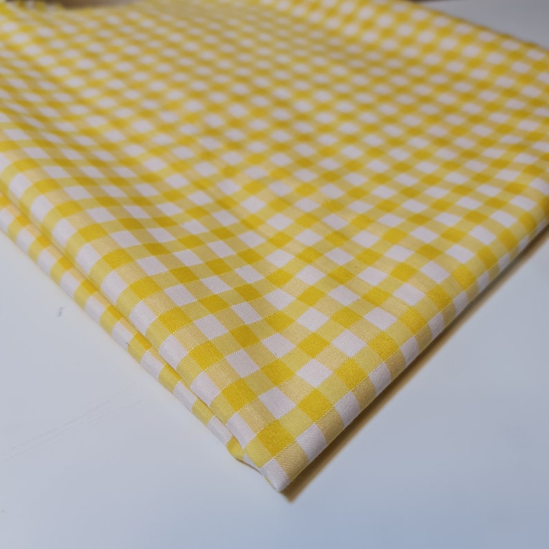 May include: Yellow and white gingham fabric with a checkered pattern.