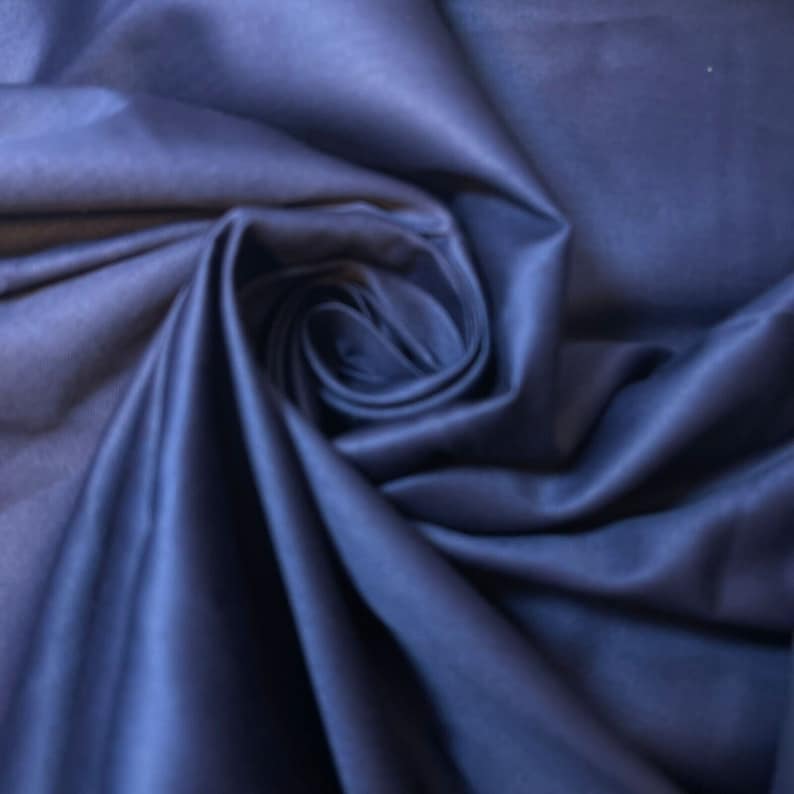 May include: A close-up of a deep blue fabric, folded and draped to create a soft, flowing texture.