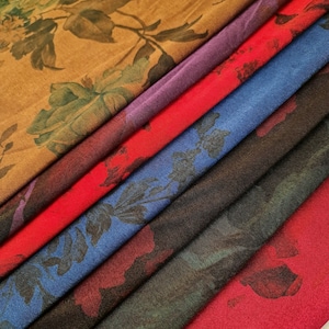 May include: A stack of six fabric swatches with floral patterns in various colors, including brown, red, purple, blue, and black.