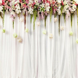 Puede incluir: Cortinas blancas y transparentes con una fila de flores blancas colgando de la parte superior.